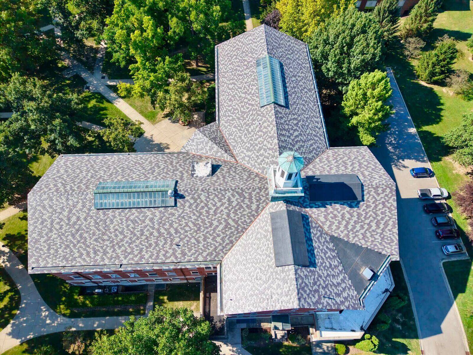 Aerial view of a civic building with a white cupola and new shingle roofing.
