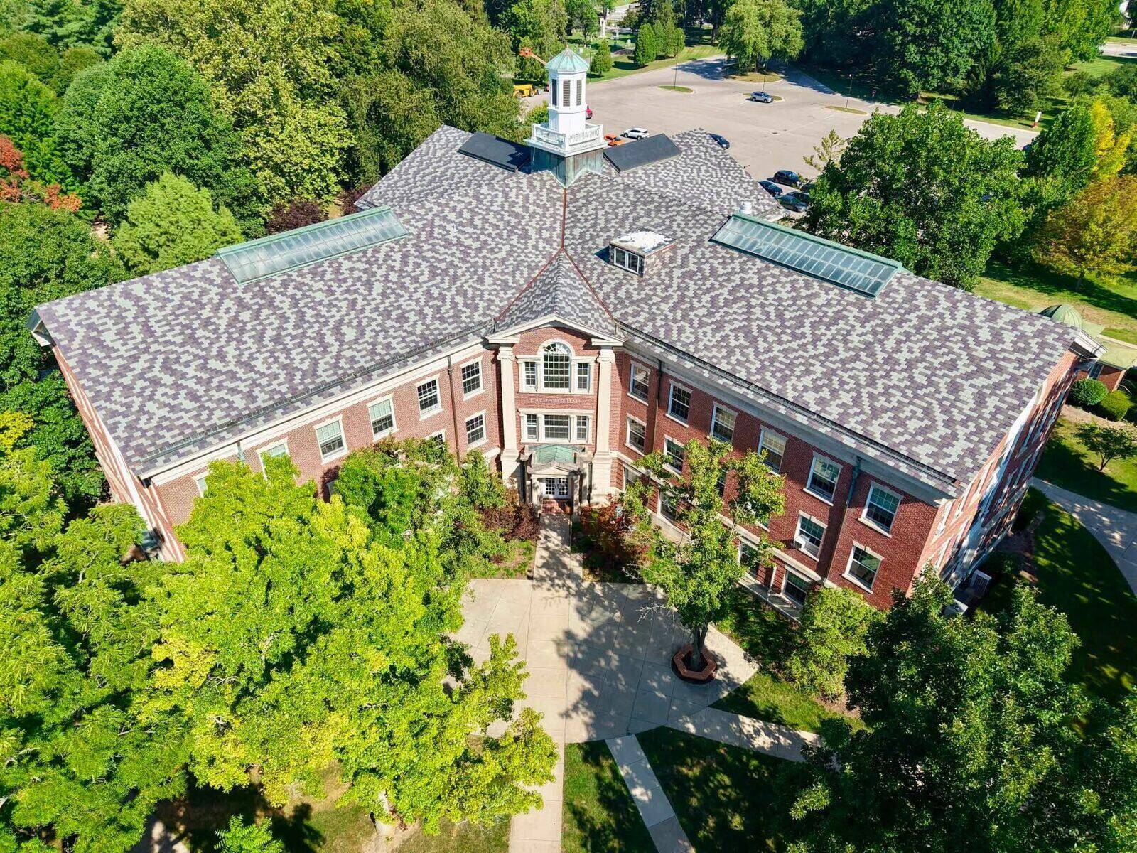 Aerial view of a large civic building with a white cupola and newly installed architectural shingle roofing, a completed Chomel and Sons job.