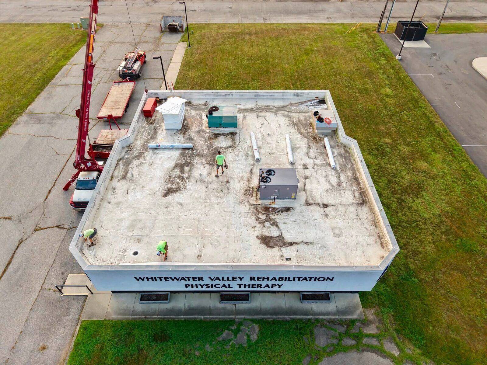 Whitewater Valley Rehabilitation and Physical Therapy mid-project: roof deck torn off, with crew and crane on site.